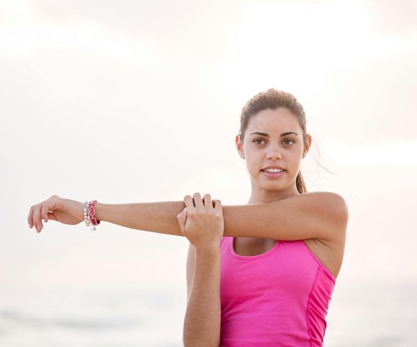 Person smiling and stretching outdoors, looking refreshed and energetic.